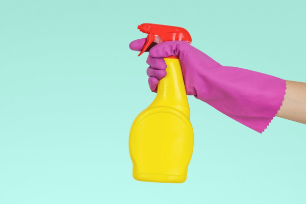 Person-holding-a-yellow-cleaning-spray-bottle